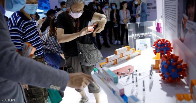 صينيون يلتقطون صورا للقاحات المحتملة لكورونا بمعرض في بكين