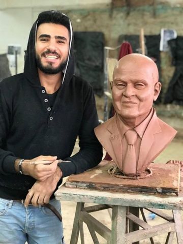 النحات الشاب رفيق فادي بجوار تمثال الدكتور العالمي مجدي يعقوب ، أستاذ جراحات القلب